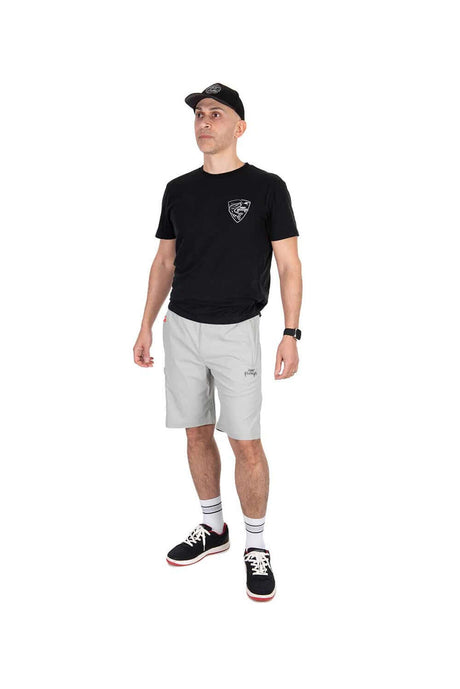 Hombre en camiseta negra y pantalón corto gris de Fox Rage, modelo Lightweight, ideal para pesca y actividades al aire libre.